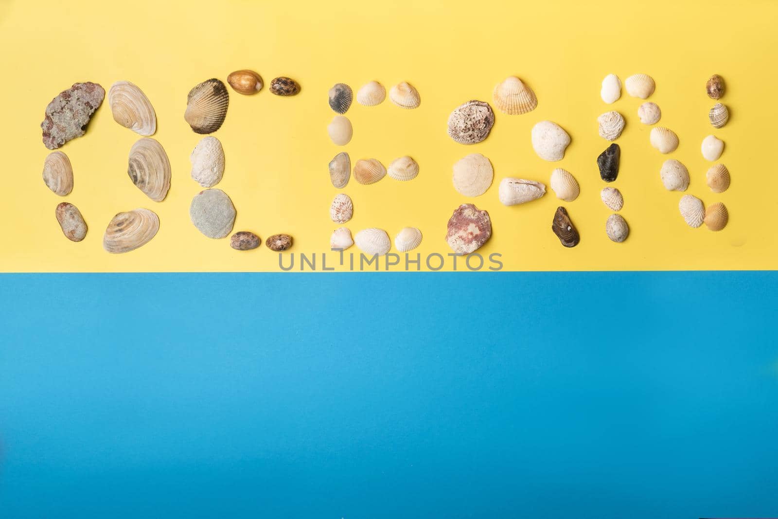 The inscription of the word ocean is made of shells on a yellow-blue background.Travel concept.