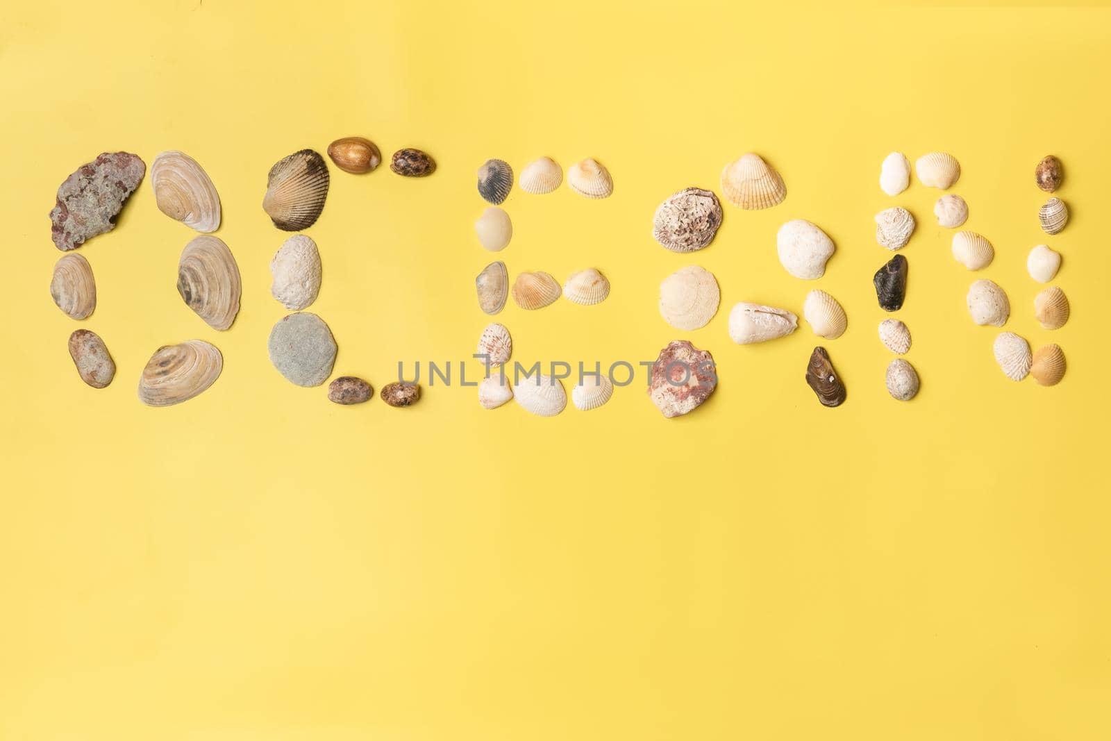 The inscription of the word ocean made of shells on a yellow background.Travel concept.