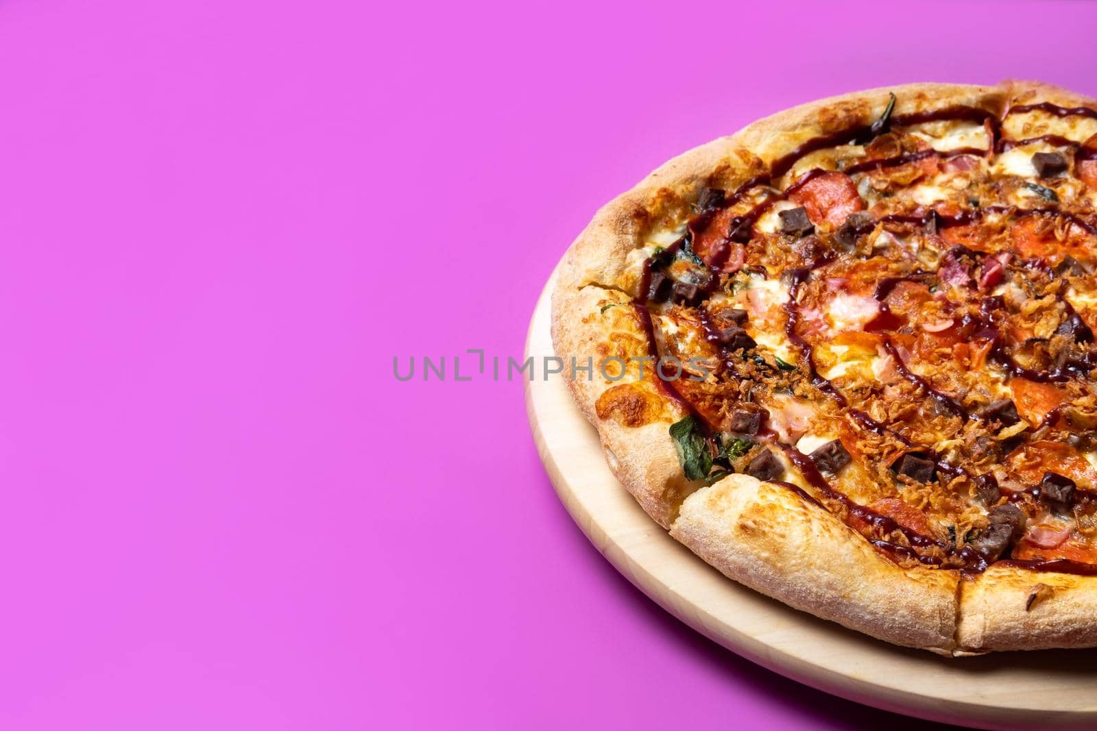 Delicious large pizza with bacon and spinach on a pink background.