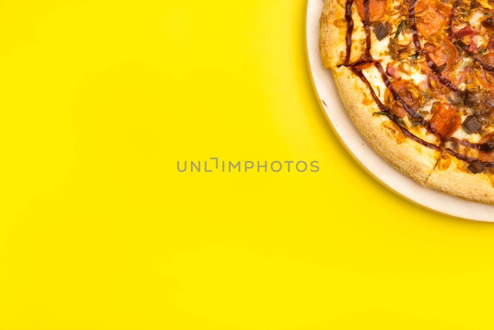 Delicious large pizza with bacon and spinach on a yellow background by Lobachad