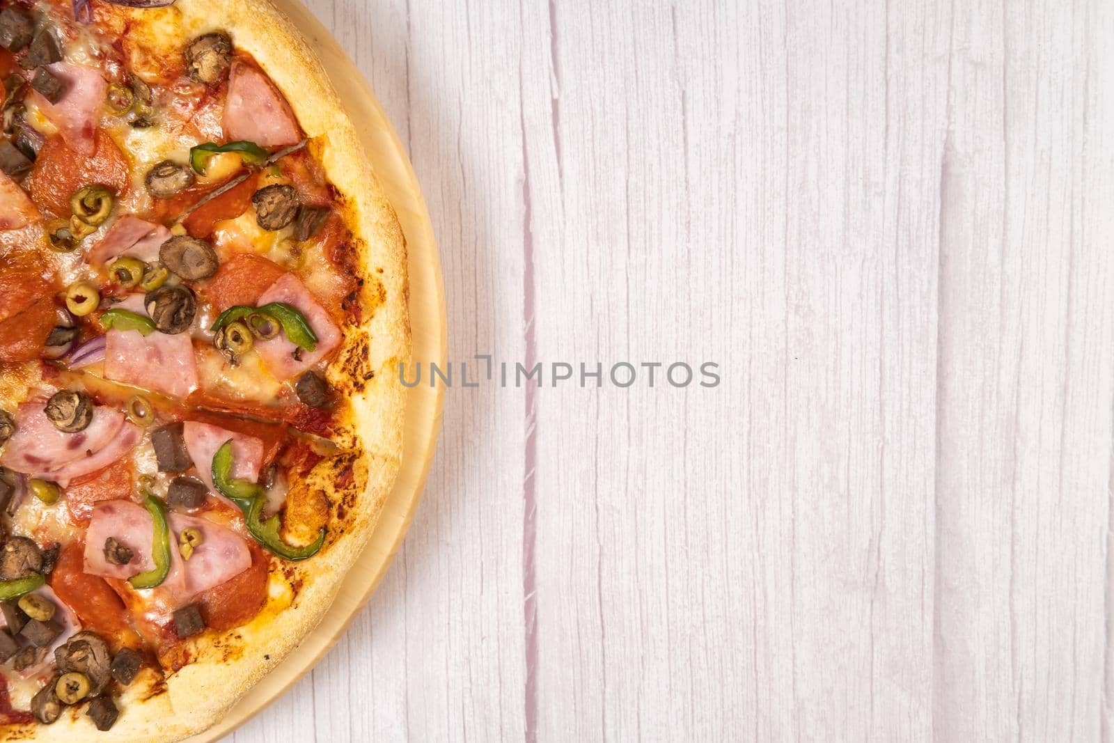 Delicious large pizza with veal and mushrooms on a light wooden background.