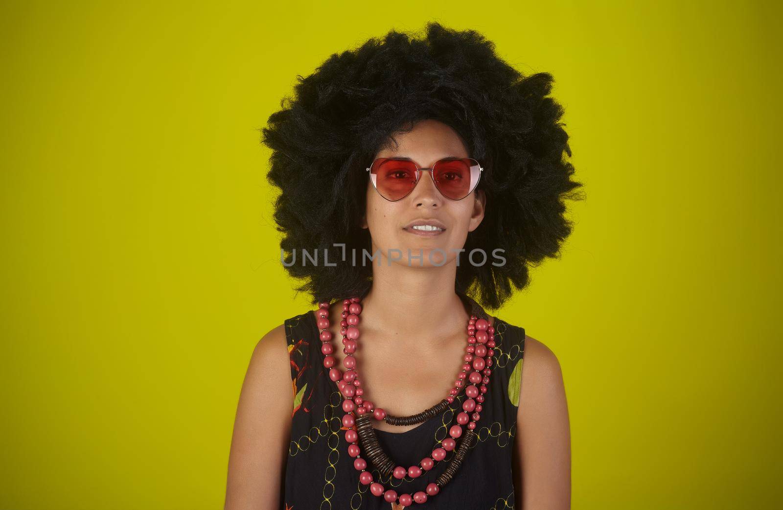 Smiling woman with afro curly hairstyle on yellow background by bepsimage