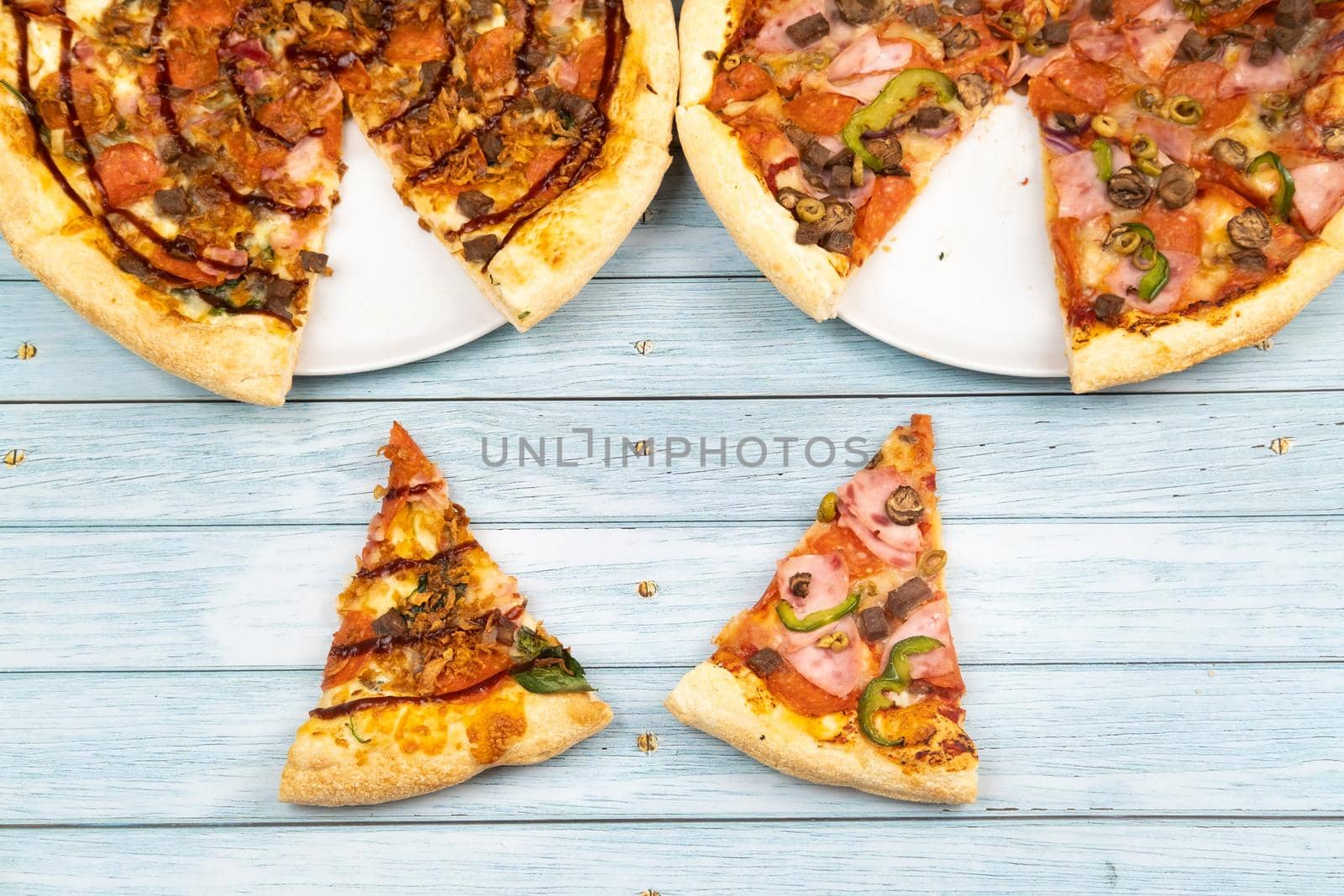 Two different delicious big pizzas on a blue wooden background.