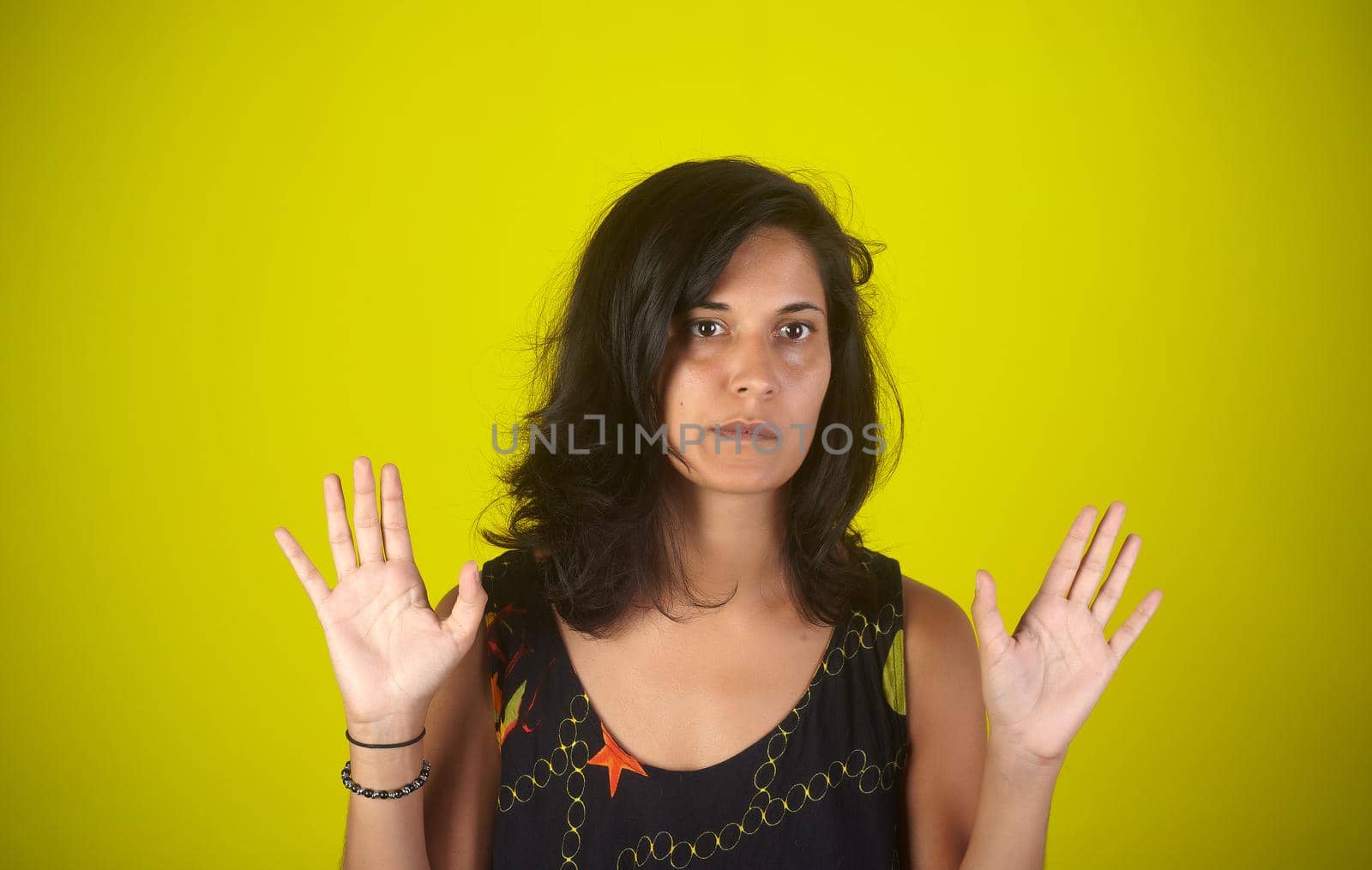 Portrait of an Indian woman with hands up on yellow background