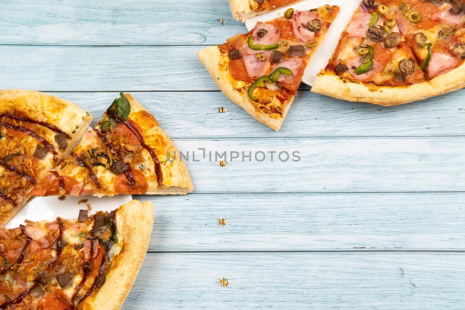 Two different delicious big pizzas on a blue wooden background.
