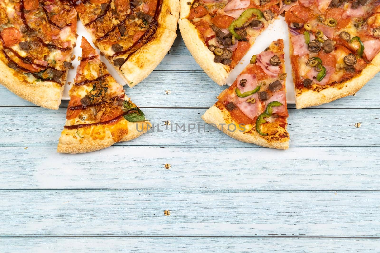 Two different delicious big pizzas on a blue wooden background.