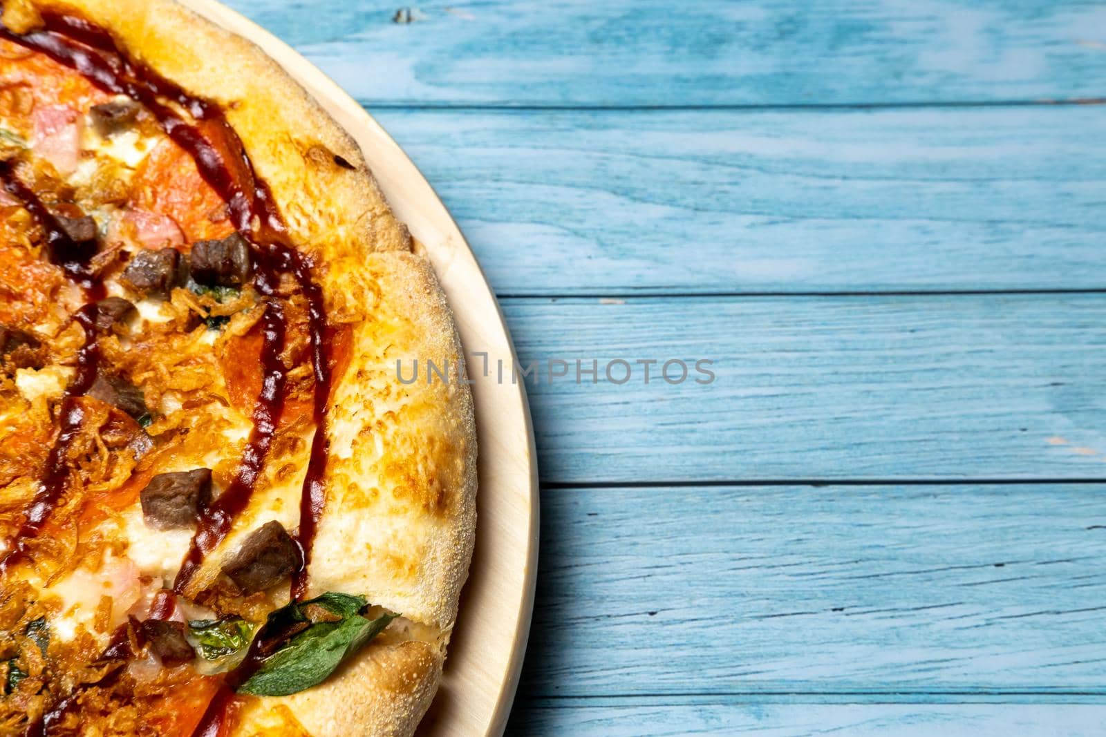Delicious large pizza with bacon and spinach on a blue wooden background.