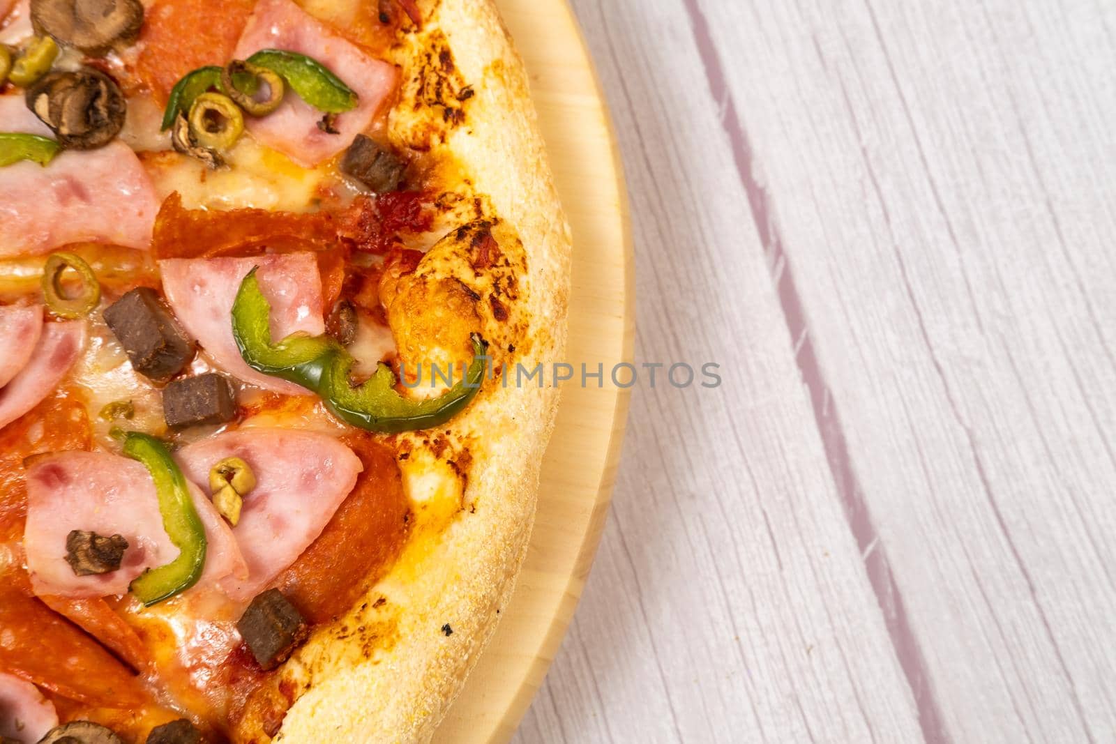 Delicious large pizza with veal and mushrooms on a light wooden background.