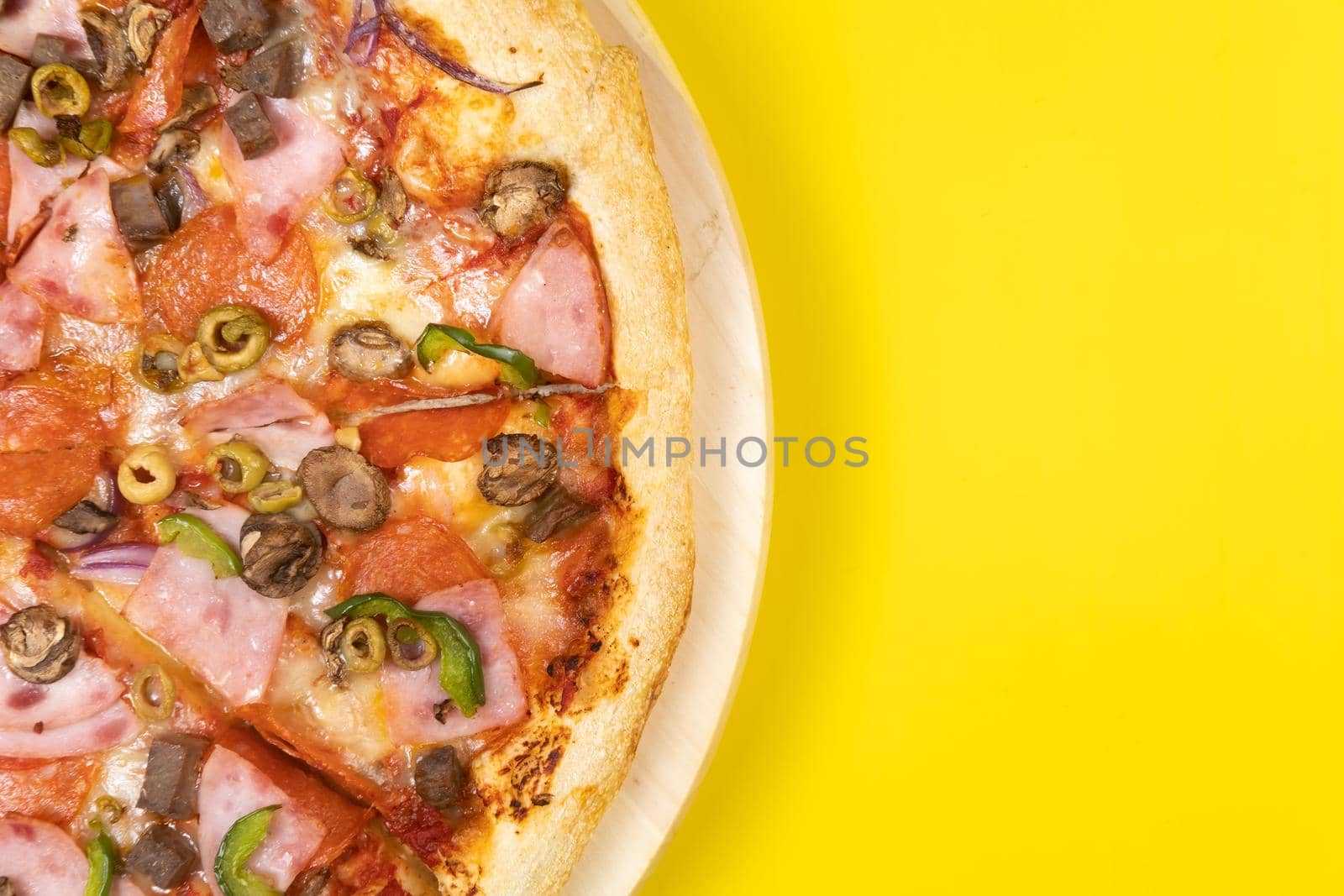 Delicious large pizza with veal and mushrooms on a yellow background.