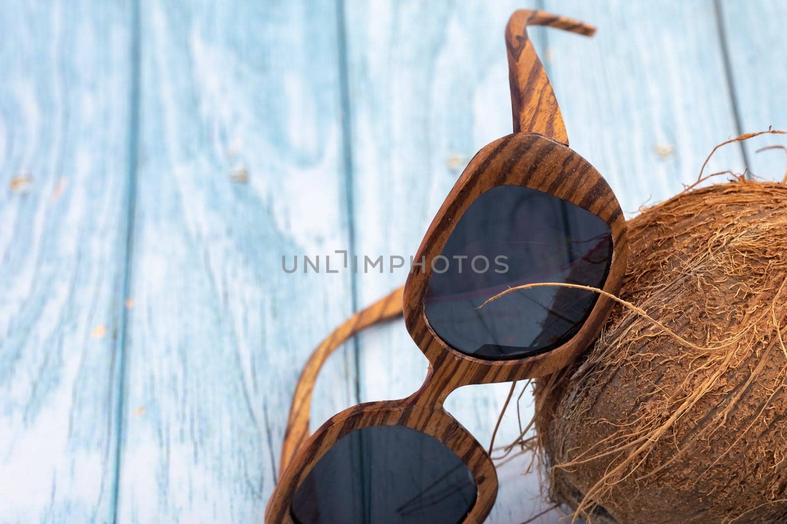 whole coconuts and wooden glasses on a blue wooden background.