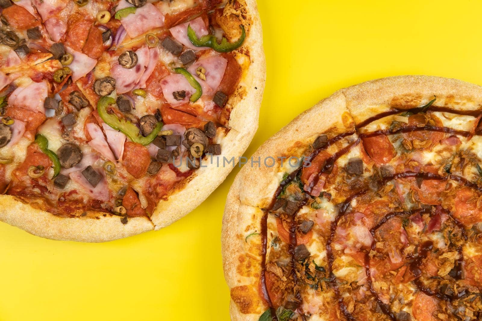 Two different Delicious big pizzas on a yellow background.