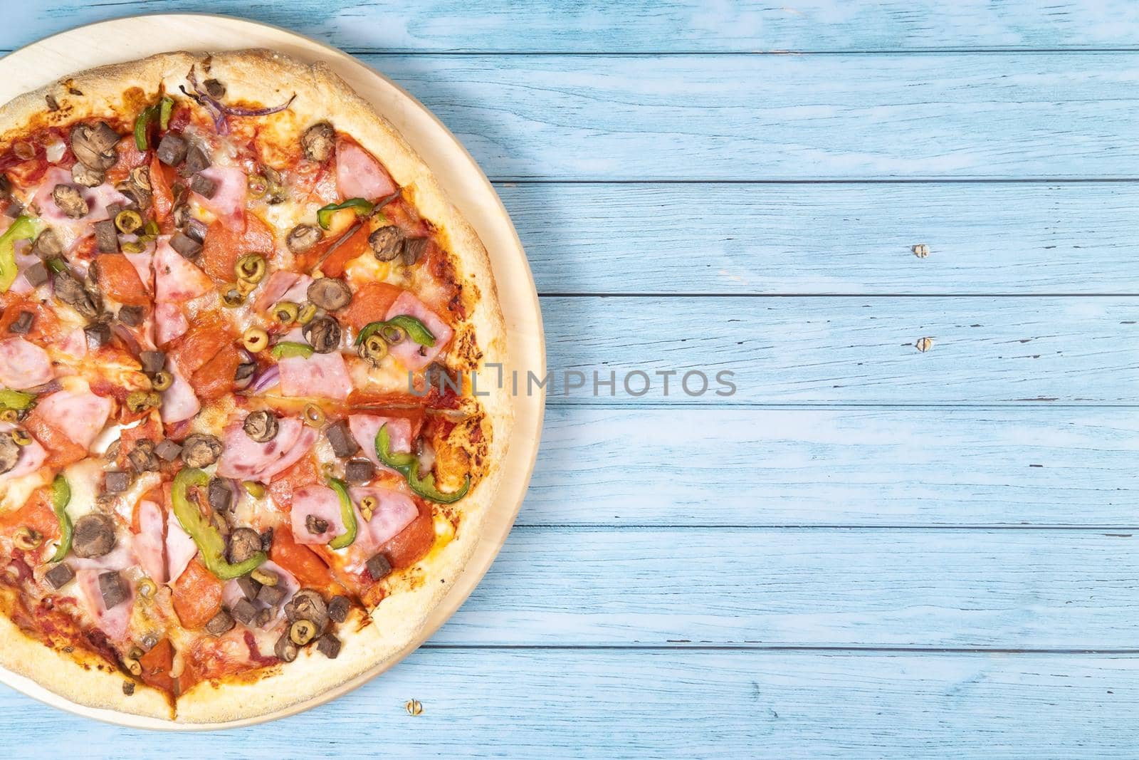 Delicious large pizza with veal and mushrooms on a blue wooden background.