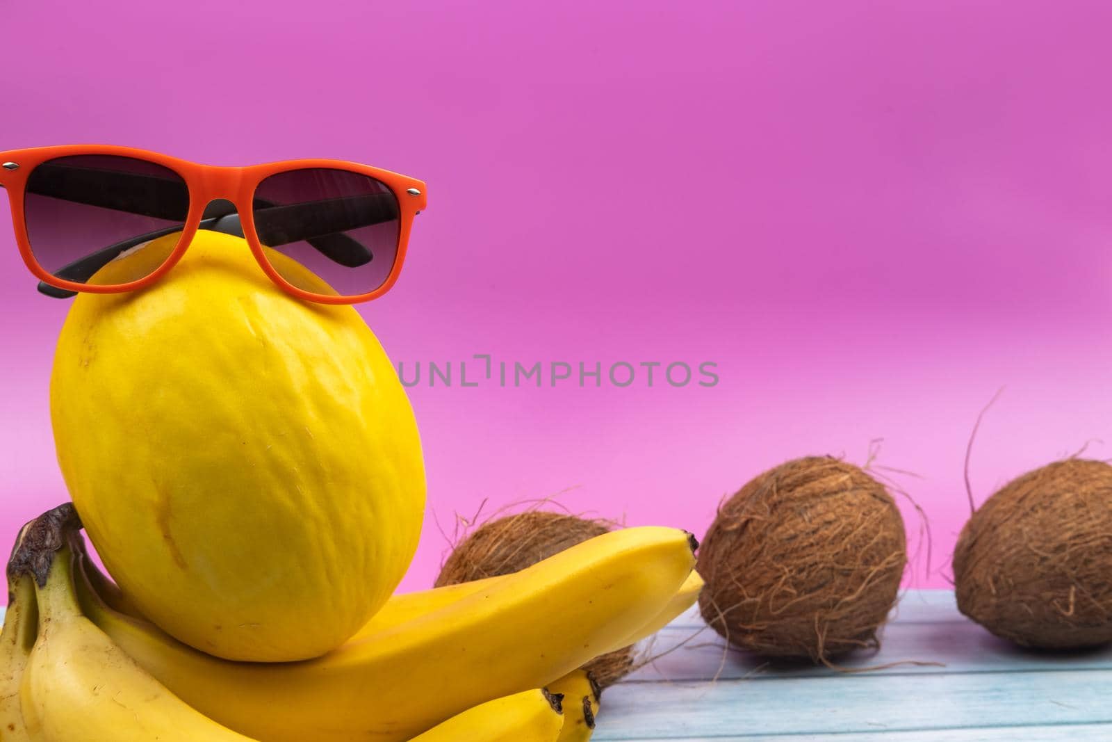 An assortment of yellow fruits and glasses lies on a pink background by Lobachad