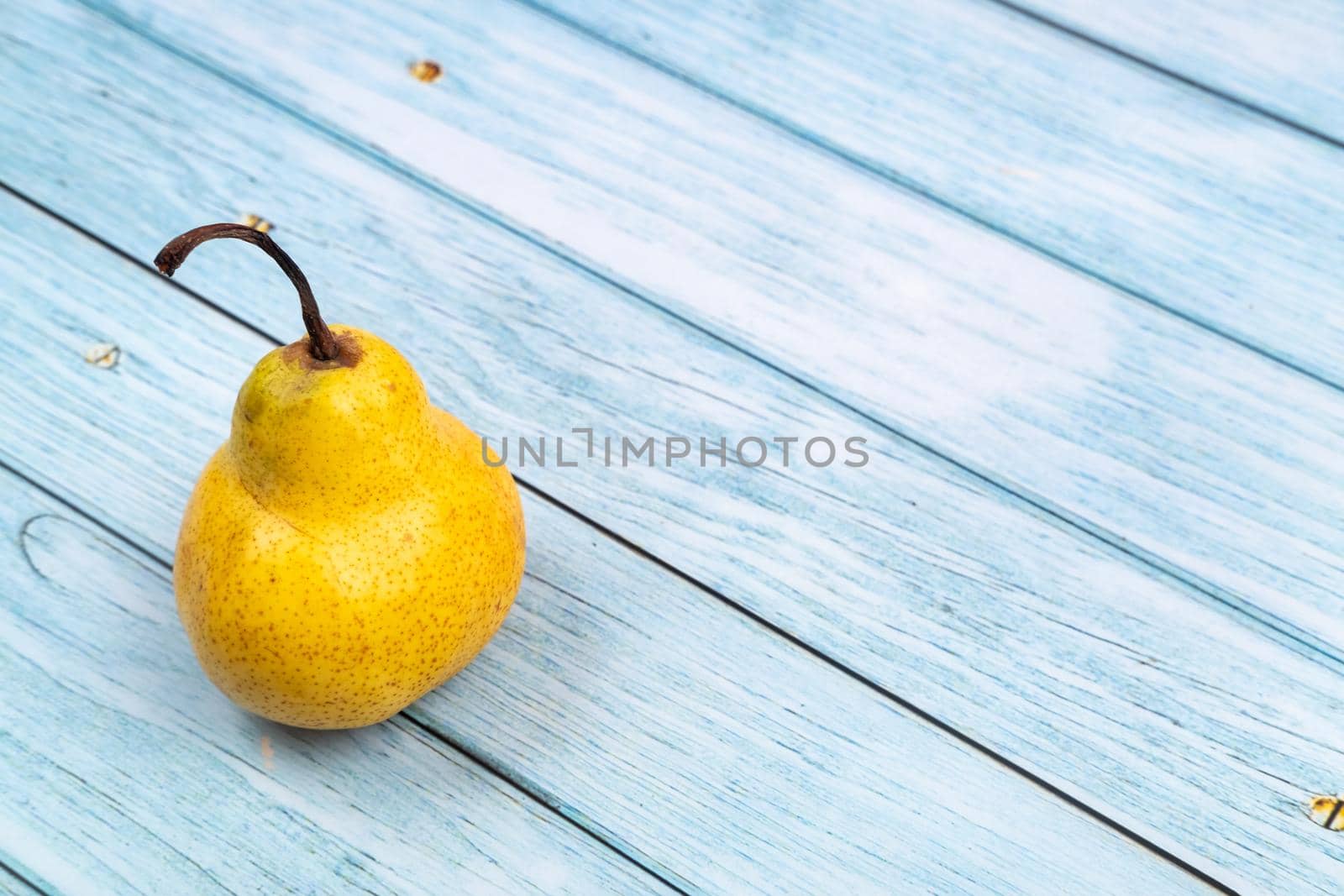 A yellow pear tree lies on a blue wooden background.Summer concept.