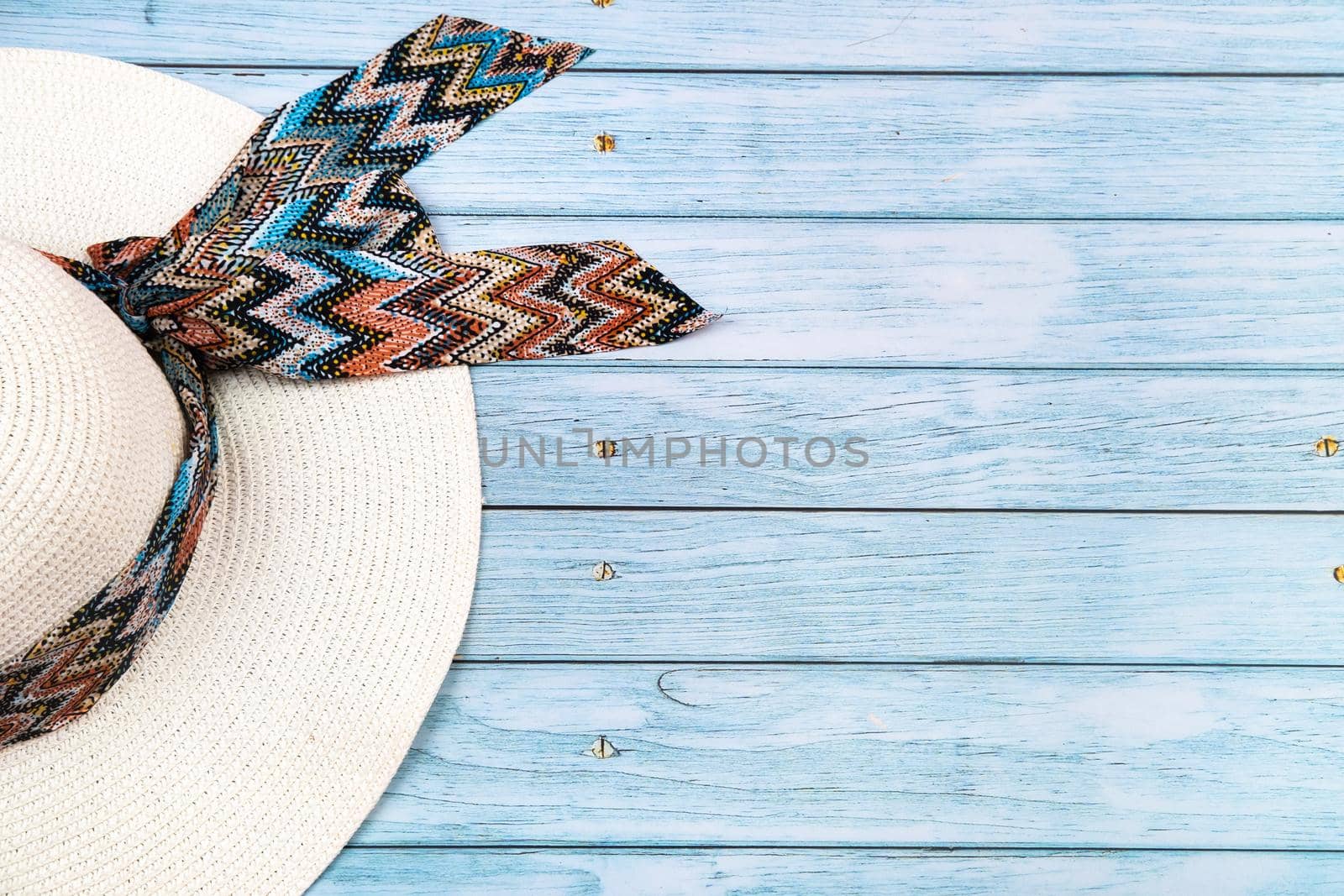 Top view of a straw white hat lying on a blue wooden background.The concept of summer holidays.
