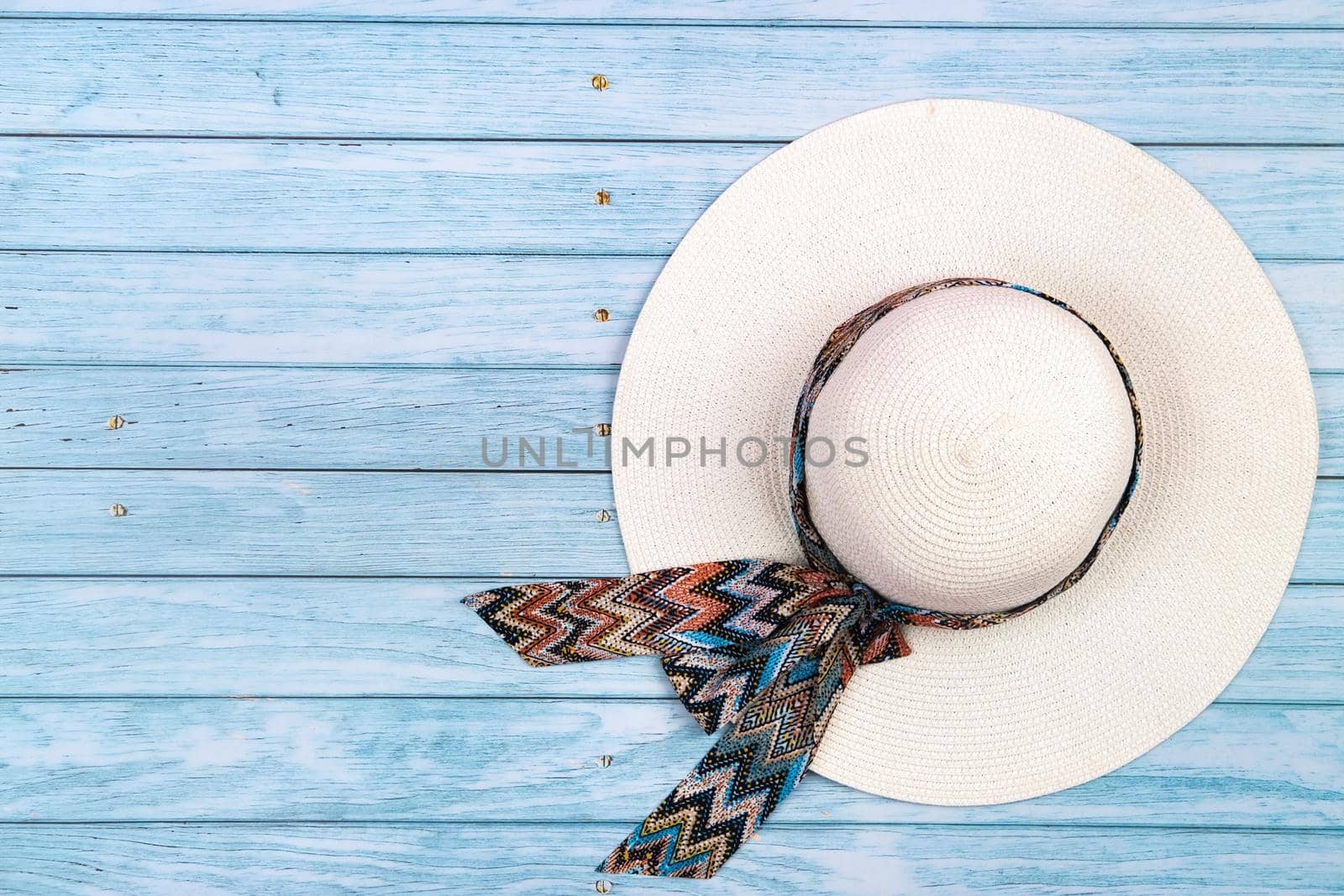 Top view of a straw white hat lying on a blue wooden background.The concept of summer holidays.