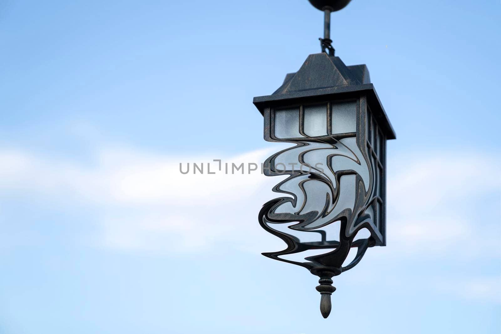 Ancient street lamp with distorted form on background blue sky. by Laguna781