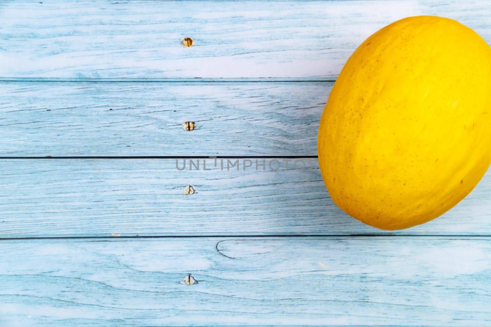 A whole yellow melon lies on a blue wooden background.Summer concept.