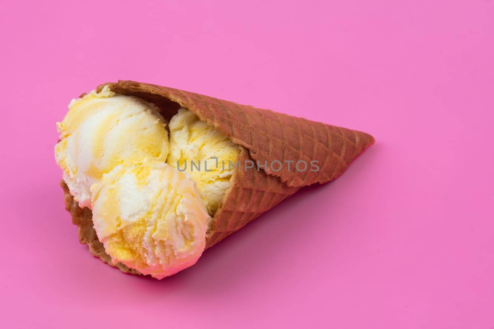 Fruit-scented ice cream balls in a waffle cone on a pink background