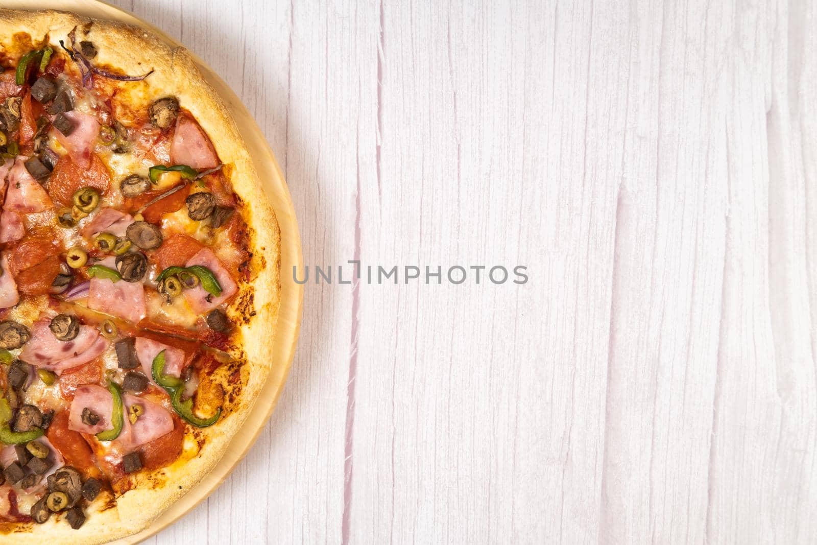 Delicious large pizza with veal and mushrooms on a light wooden background.