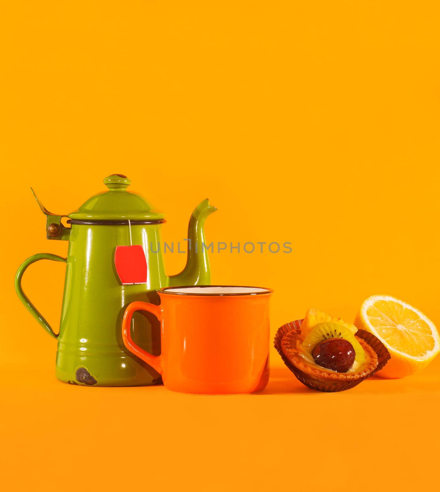 Set of vintage teacup, orange cup, lemon and pastry on orange background. Copy space on top