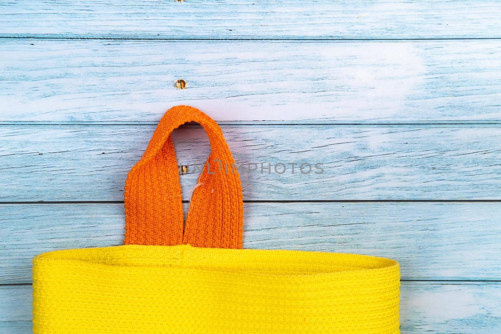 An empty bag with a handle lying on a blue wooden background.