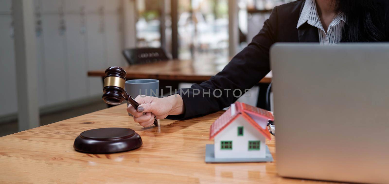 Real Estate Law concept. Gavel on sounding block in hand's female judge at a courtroom, working for the insurance compensations. report the case on table in modern office. by wichayada