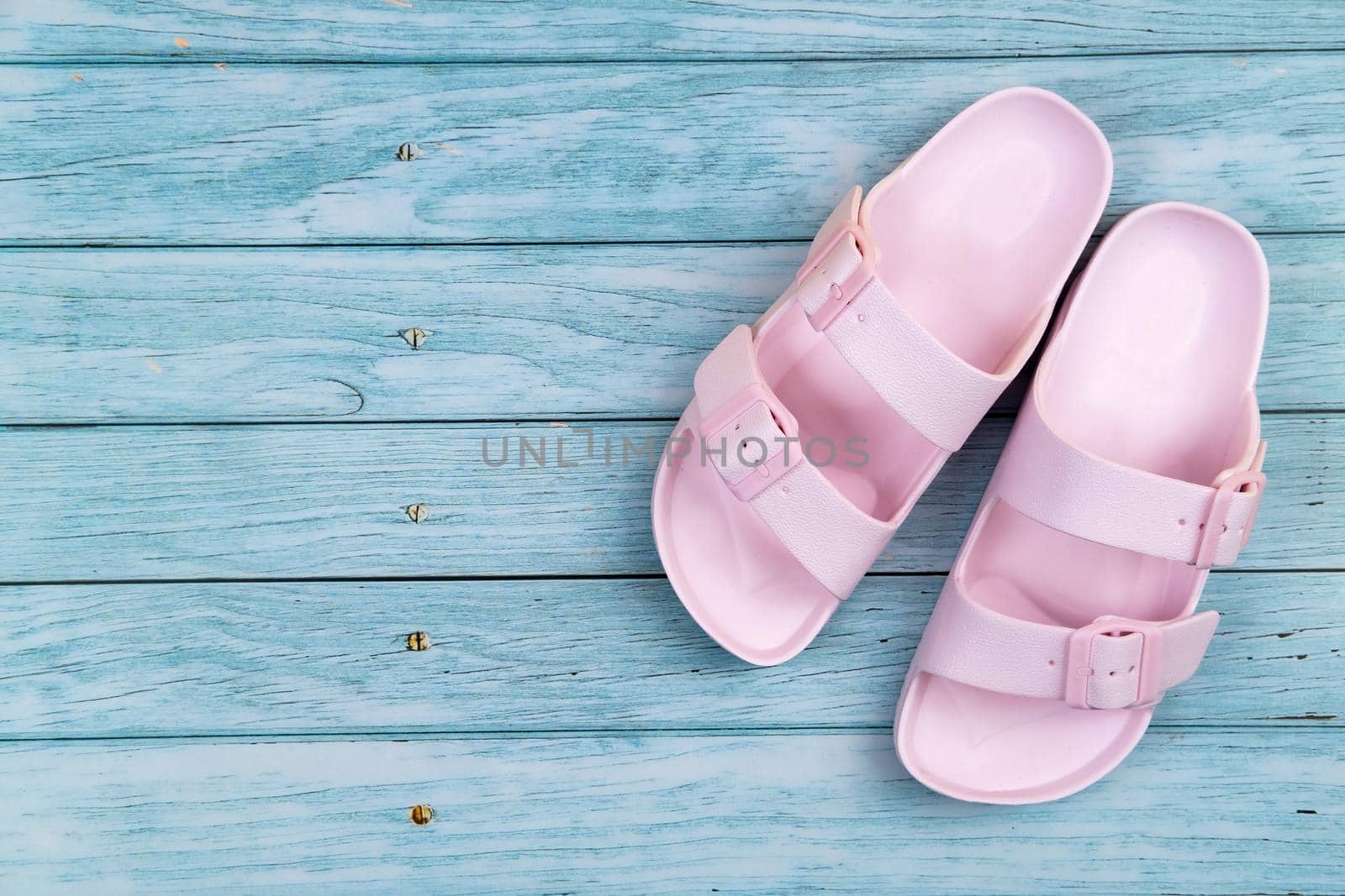 Pink sneakers stand on an isolated blue wooden background.