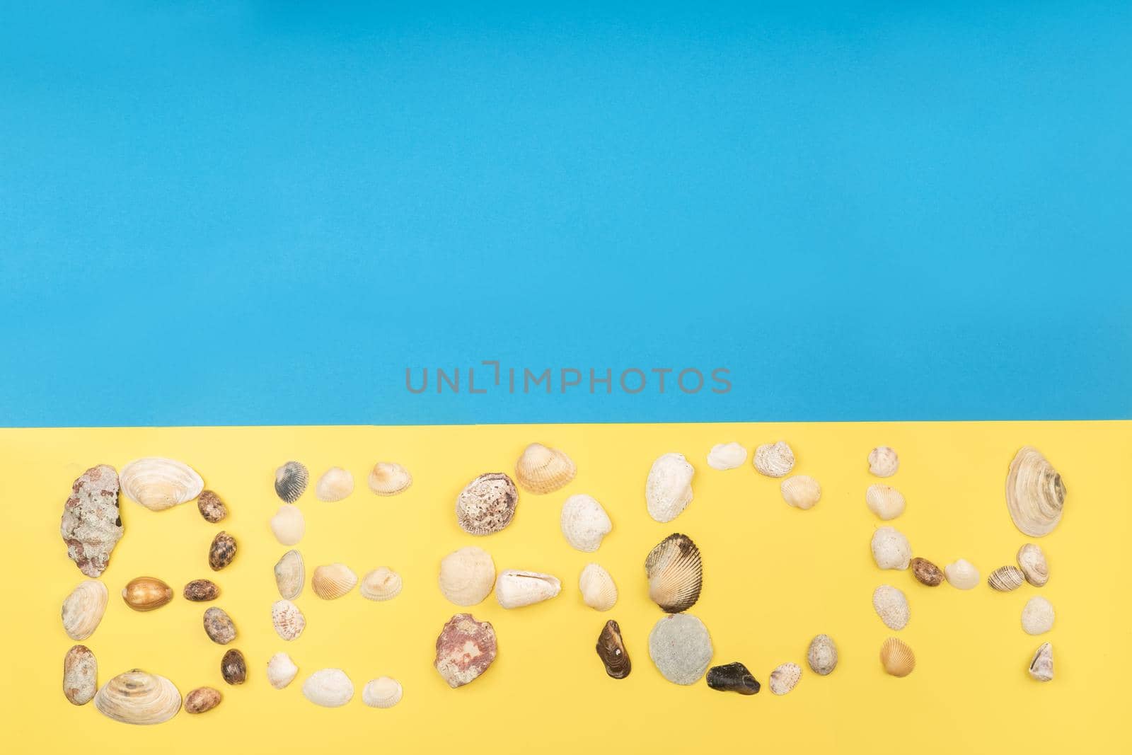 The inscription of the word beach is made of shells on a yellow-blue background.Travel concept.