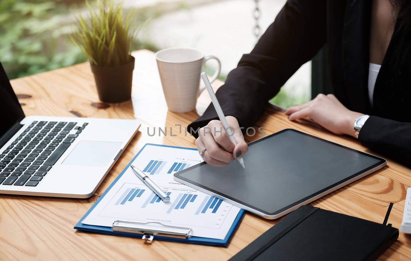 Business woman or accountant hand using calculator, working on taplet and laptop computer with documentary data graph paper on the table at modern home office. Online marketing concept..