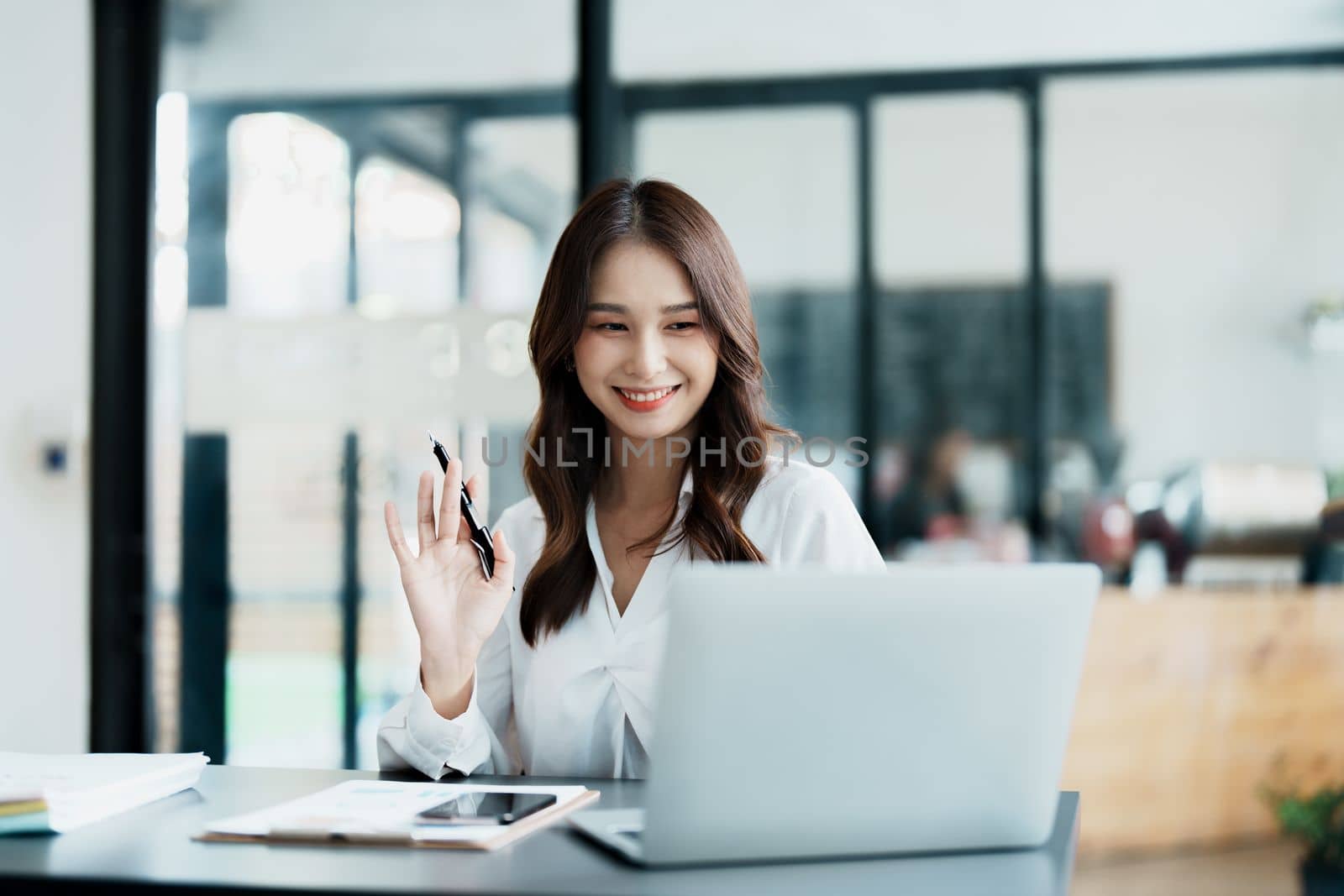 Portrait of a beautiful Asian teenage girl using computer for video conferencing at office by Manastrong