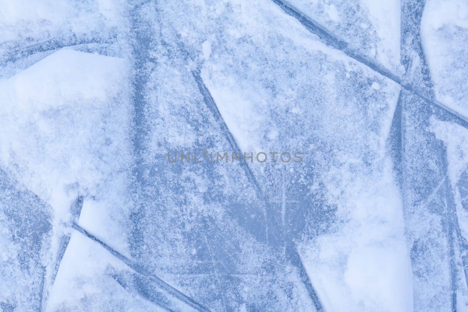 Empty ice rink with skate marks after the session outdoor. skating ice rink texture covered with snow in daylight. Close up of blue ice rink floor, copy space