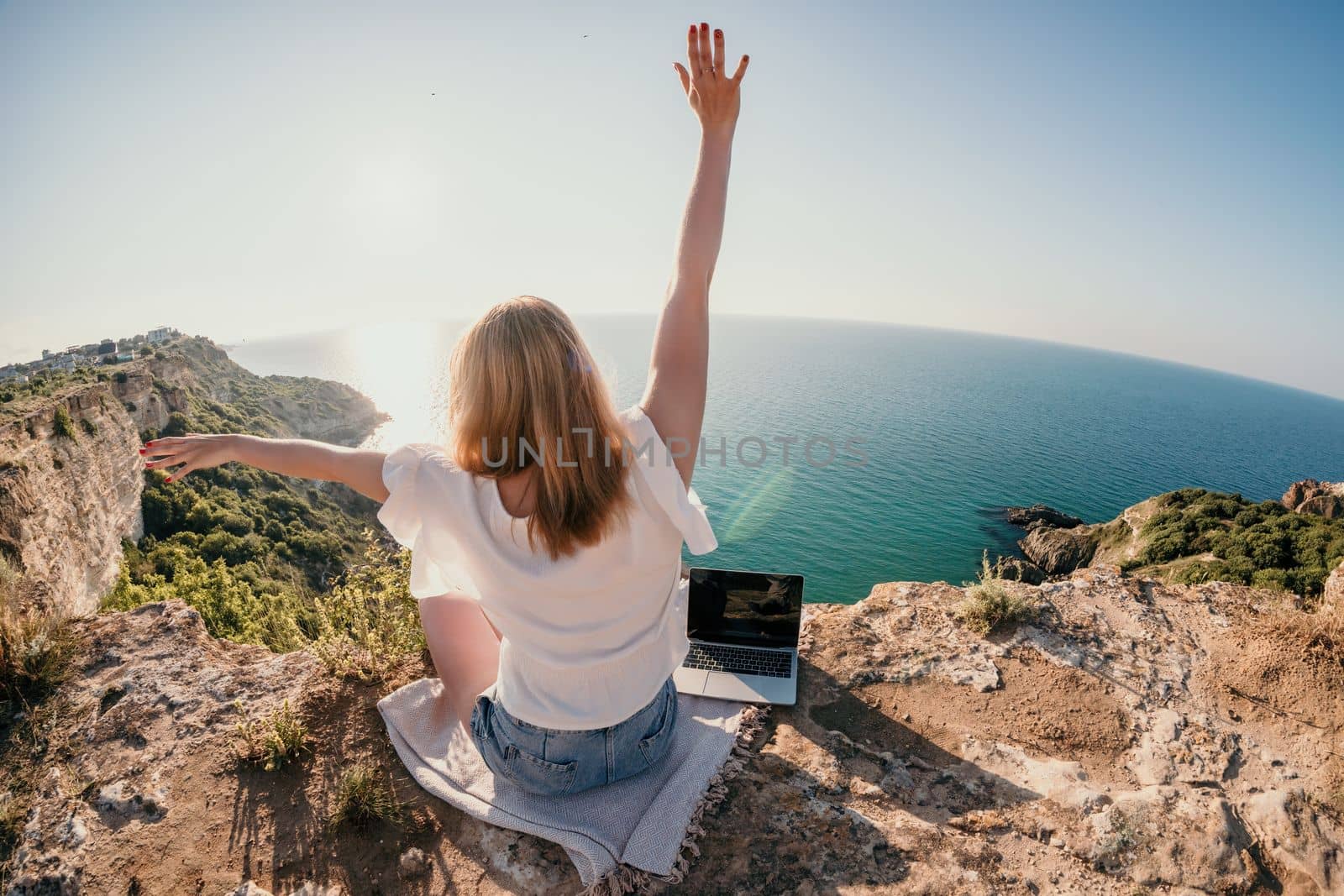 Woman sea laptop. Business woman in yellow hat working on laptop by sea. Close up on hands of pretty lady typing on computer outdoors summer day. Freelance, digital nomad, travel and holidays concept.