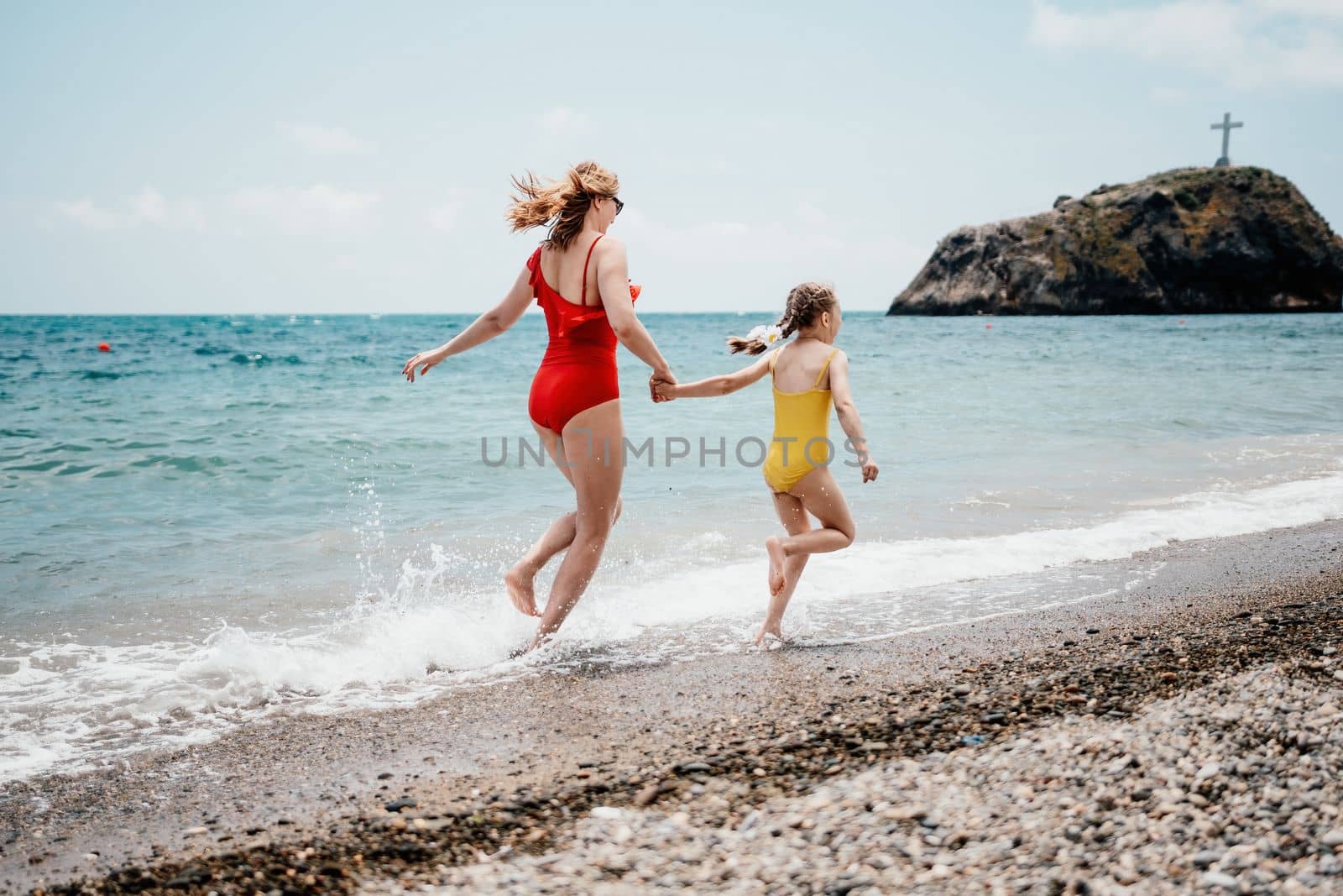 Happy loving family mother and daughter having fun together on the beach. Mum playing with her kid in holiday vacation next to the ocean - Family lifestyle and love concept.