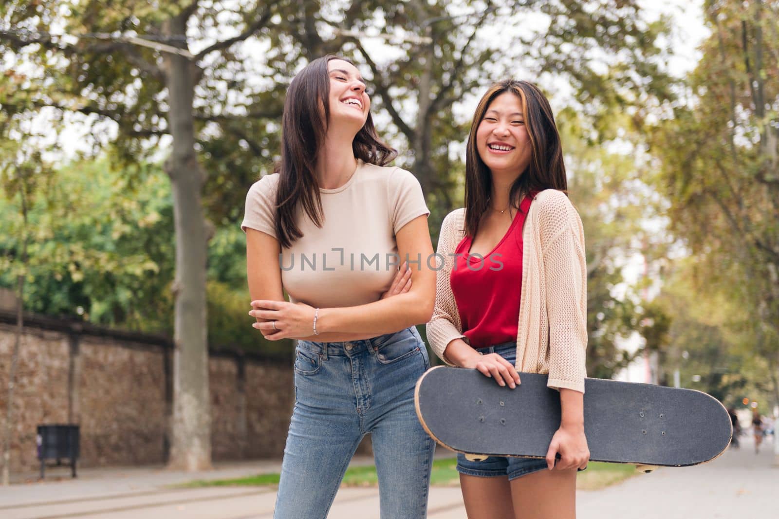 two young women laughing happy and smiling looking at camera, concept of female friendship and teenager lifestyle, copy space for text