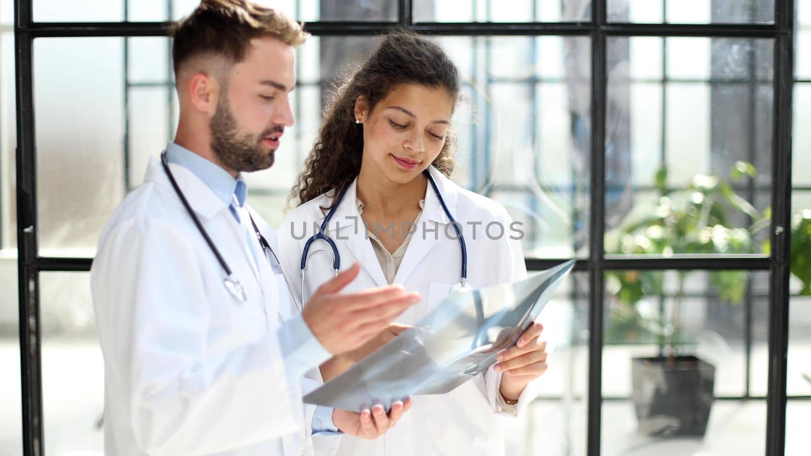 Two busy doctors working with papers and x-rays in hospital lobby