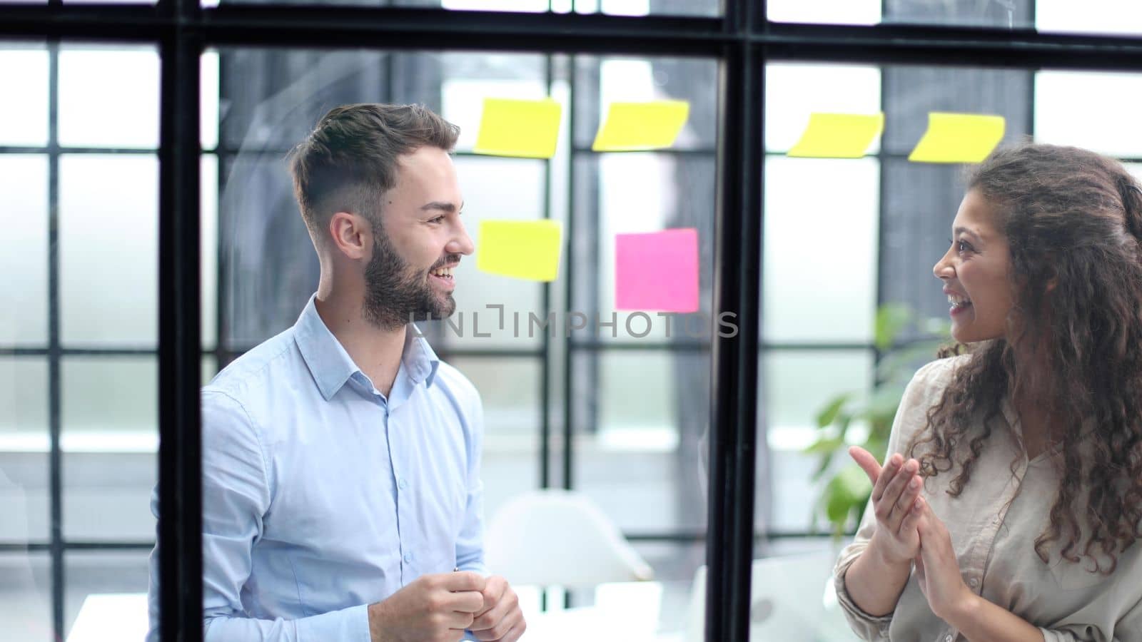 Businessman writing sticking adhesive notes on glass wall in office and team help to creative idea, Teamwork working write work stickers by Prosto