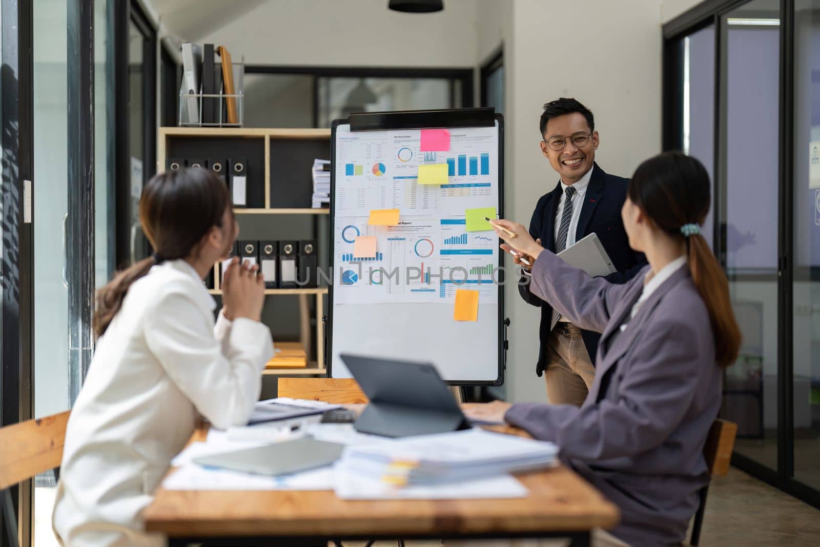 Business adviser explaining business plan strategy on flipchart to colleagues, male coach or adviser giving presentation at briefing, reporting about results or growing sales.