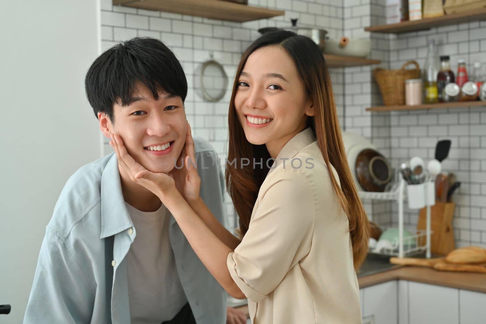 Beautiful young couple enjoying spending time together while standing in modern kitchen.