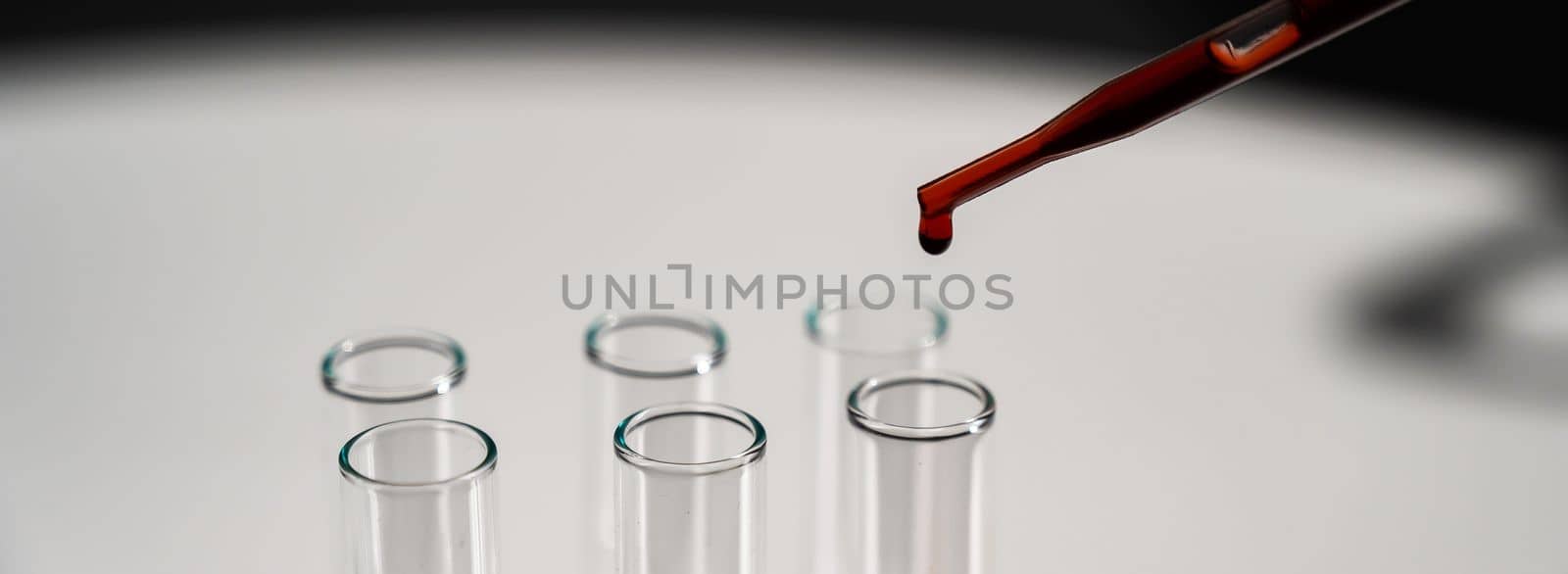 Close-up of a laboratory assistant dripping blood from a pipette into a test tube