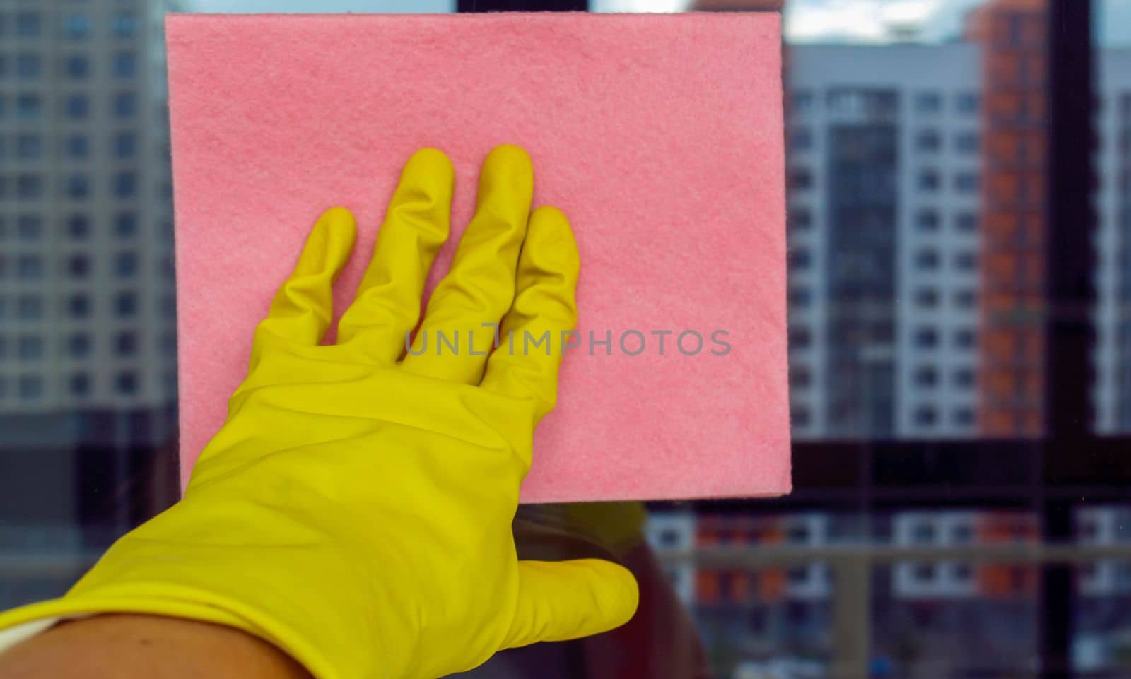 Window washing. In the photo, a hand in a rubber glove with a rag washes a window.