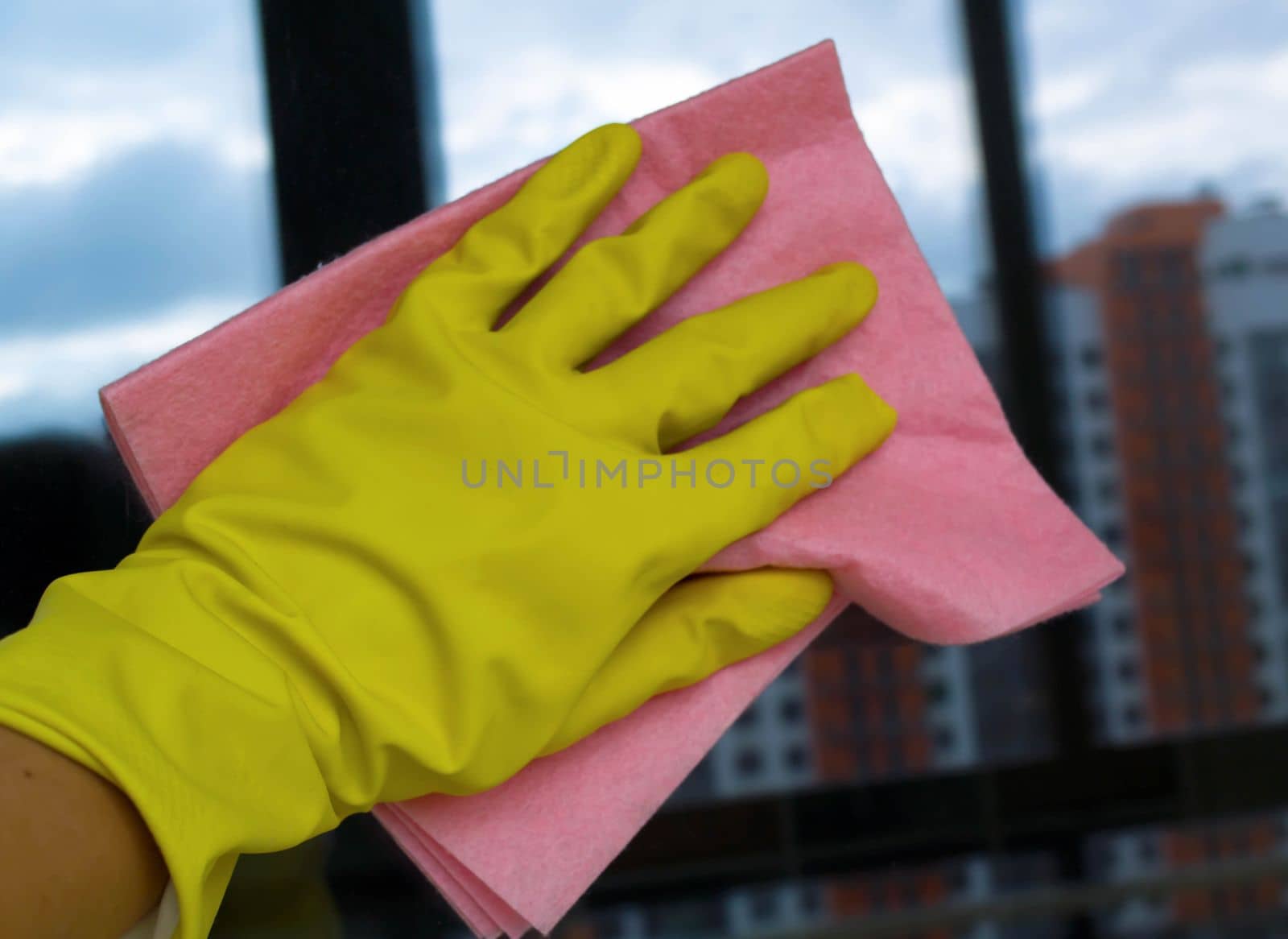 Window washing. In the photo, a hand in a rubber glove with a rag washes a window.