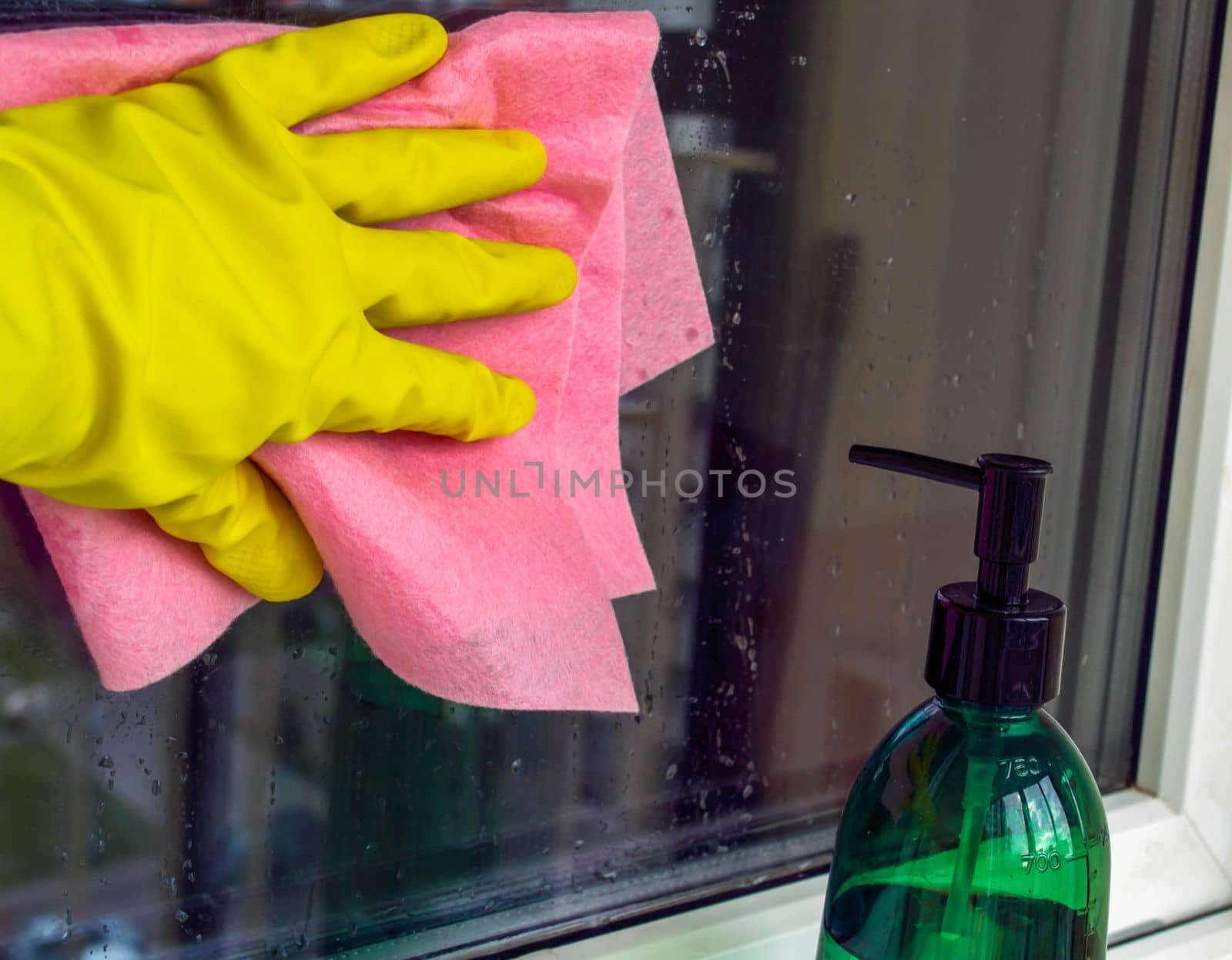Window washing. In the photo, a hand in a rubber glove with a rag washes a window.