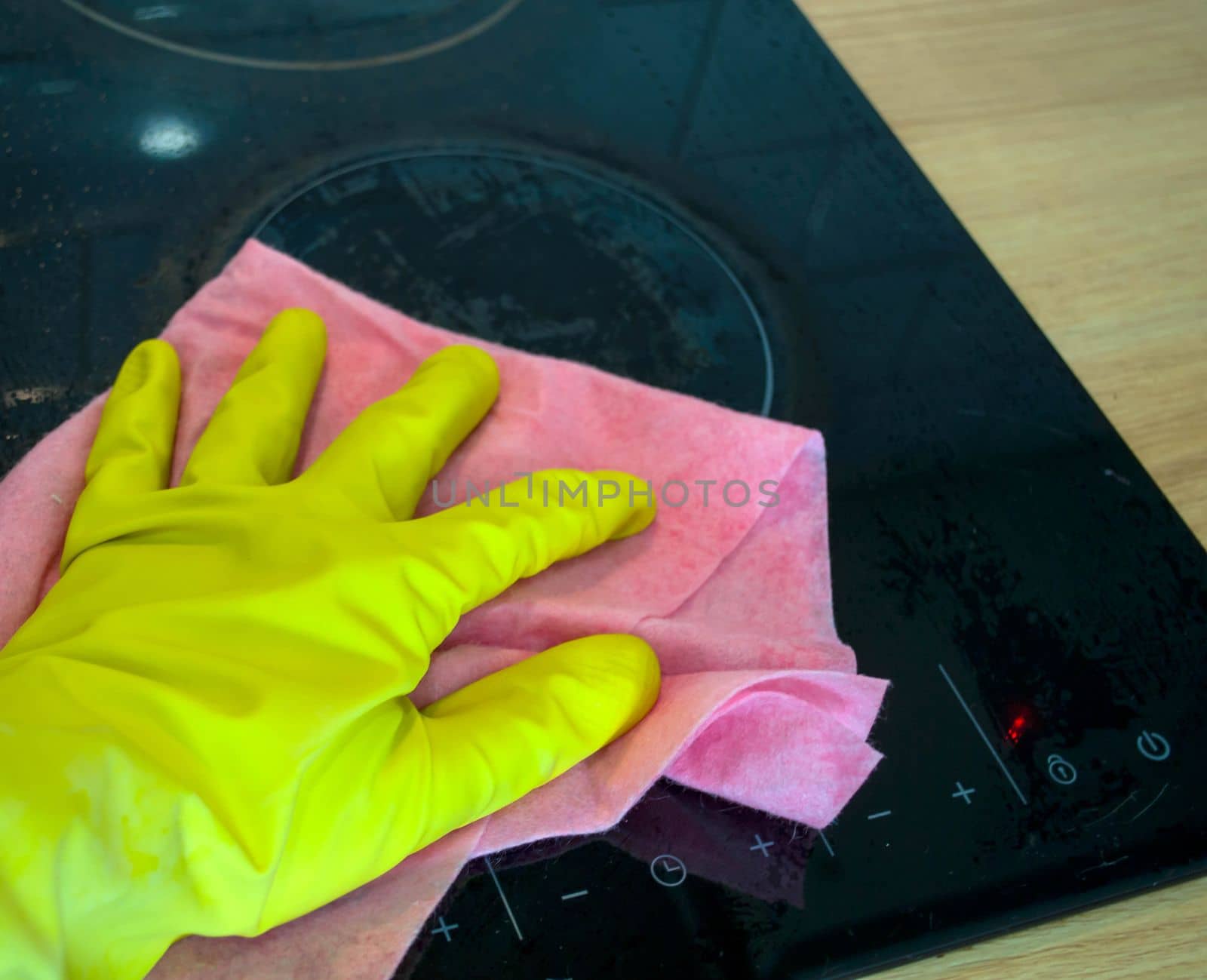 Cleaning. In the photo, a hand in a rubber glove washes a stove with a rag.