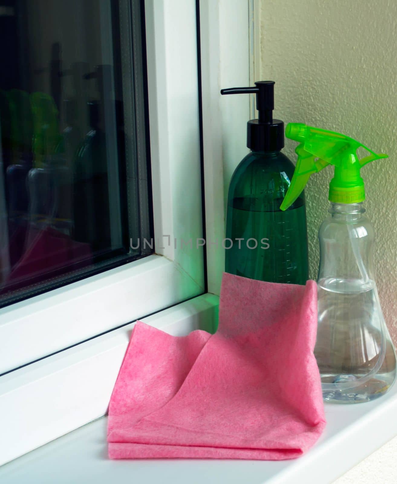 Window washing. In the photo, a sprayer, a rag are on the windowsill.