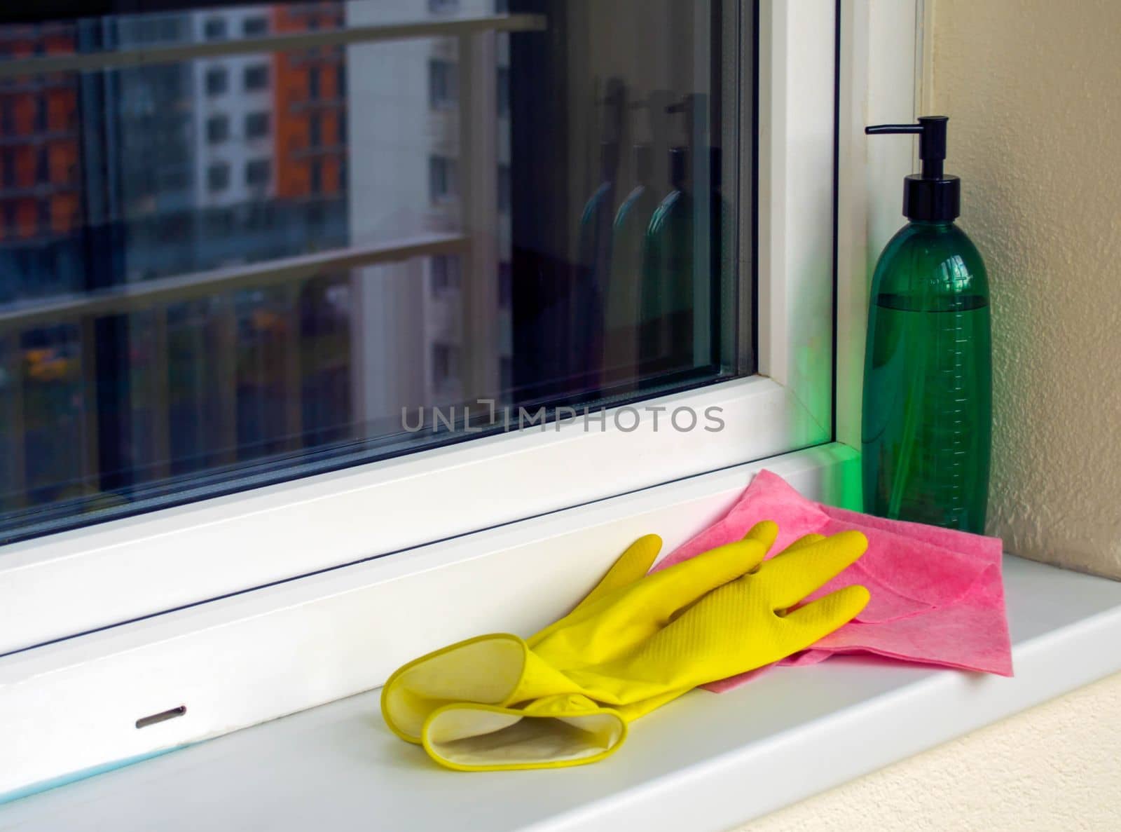 Window washing. In the photo, the sprayer, rag and rubber gloves are on the windowsill.