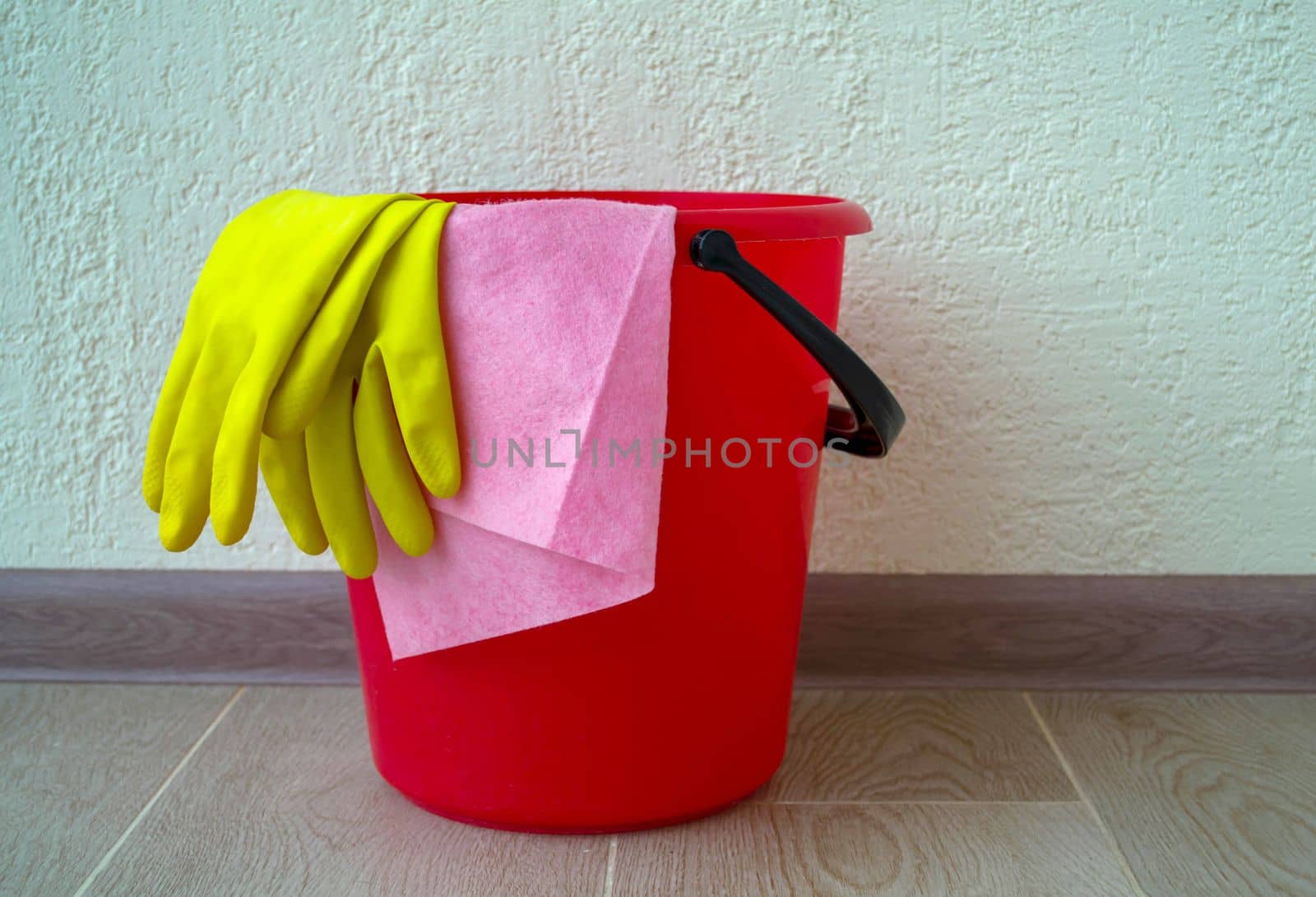 House cleaning. The photo shows a red bucket, rubber gloves and a rag.