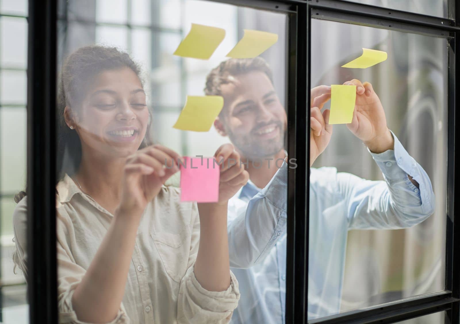 A group of business people behind a glass wall in the office sticking notes