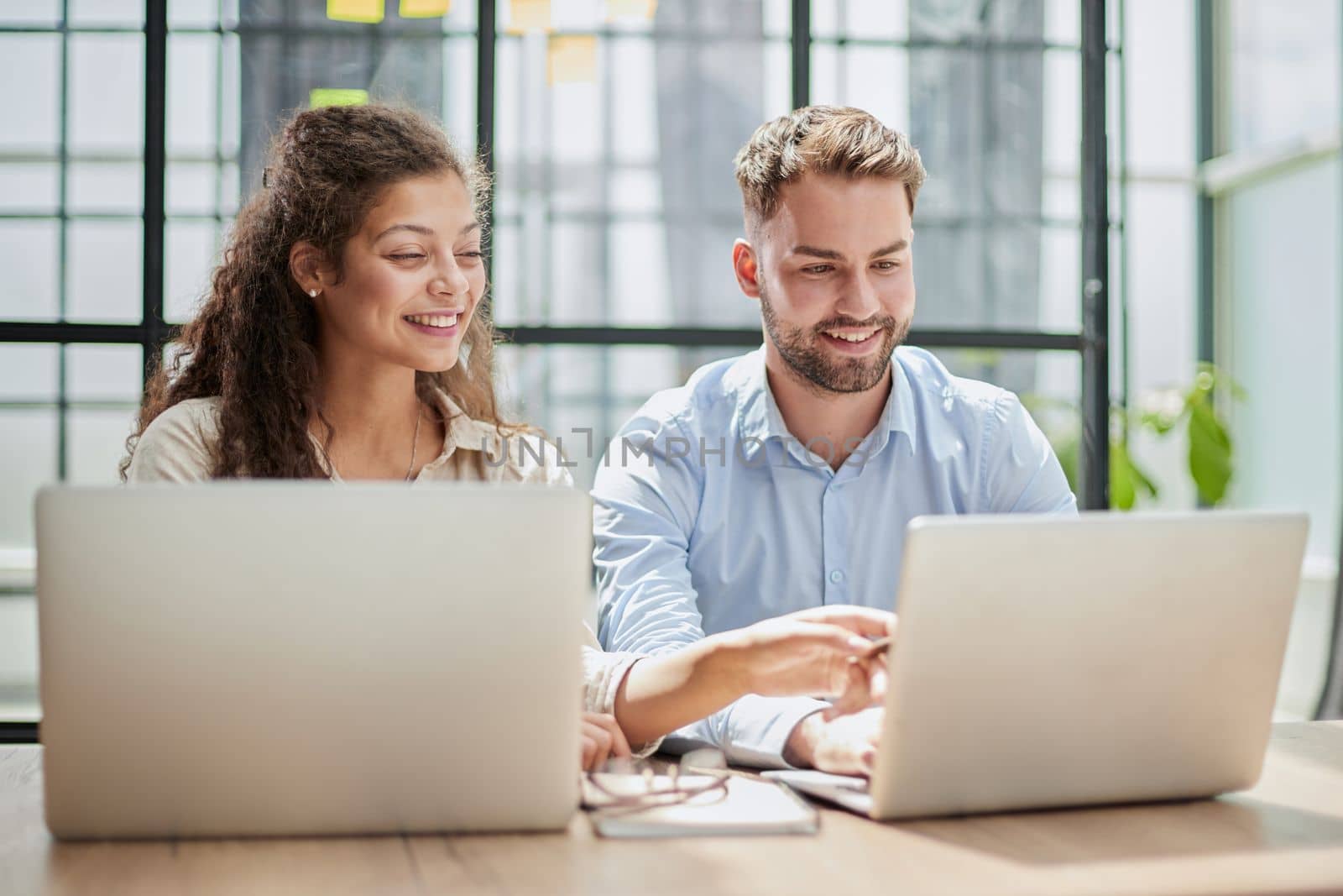 Attractive man and charming woman is pointing at the laptop screen, laughing together, resting by Prosto