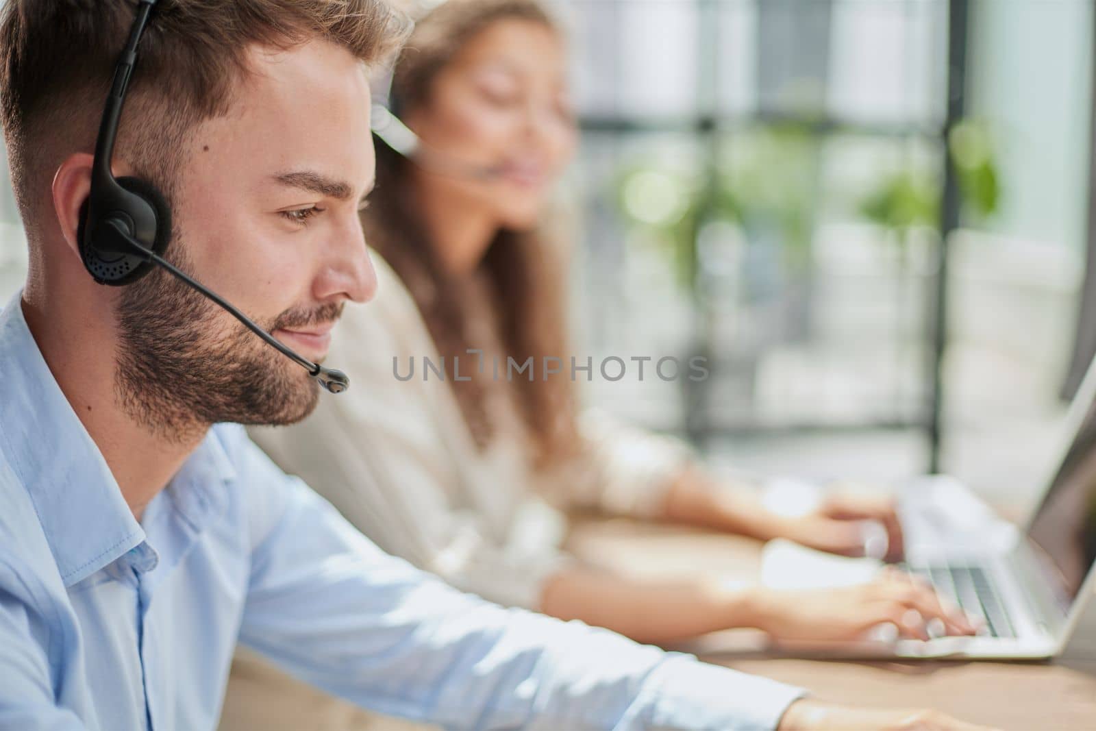 Handsome male customer service agent working in call center office as a telemarketer.